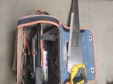 un sac à outils posé par terre, contenant des outils