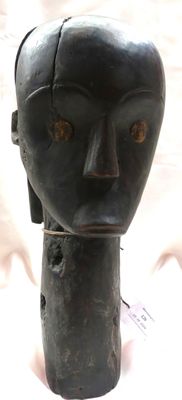 une sculpture noire représentant la tête d'un homme, posée sur une table