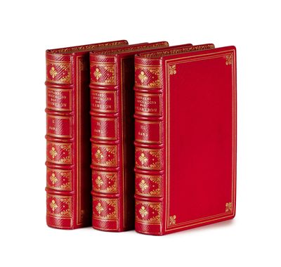 trois livres rouges aux tranches dorées sont empilés les uns sur les autres