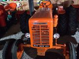 an orange tractor parked in a garage with other tractors