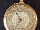 a gold pocket watch on display on a black surface