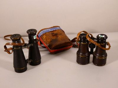 trois paires de jumelles et une pochette posées sur une surface blanche