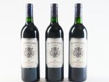 three bottles of wine are lined up on a white surface