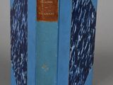 an old book with a blue cover sitting on top of a table