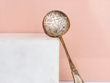 a gold spoon sitting on top of a marble block next to a pink wall