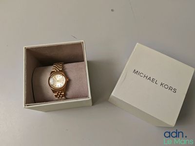 une montre Michael Kors dans son coffret, posée sur une table