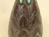 a brown vase with a green top on a white surface
