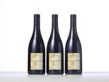 three bottles of wine are lined up on a table