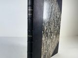 a black book sitting on top of a table next to a white wall