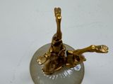 a gold statue of a bird on a glass plate