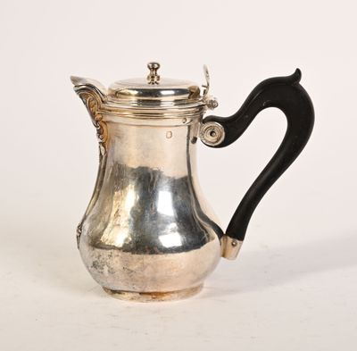 une cafetière ancienne en argent avec une poignée noire sur une surface blanche