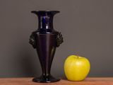 a blue vase and an apple sitting on a table