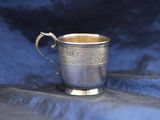 a silver cup with a handle on a blue cloth
