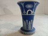 un vase bleu posé sur une surface blanche