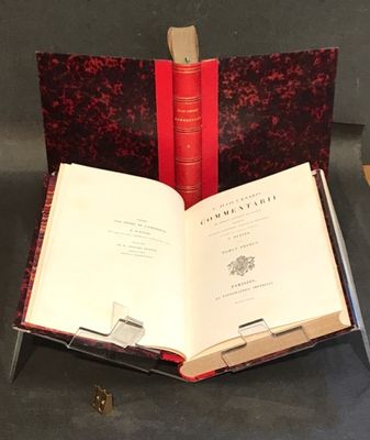un livre ouvert posé sur une table, à côté de deux livres rouges
