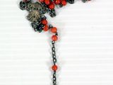 beaded cross with red beads and a black cross on a white background