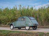 a small green car driving down a dirt road
