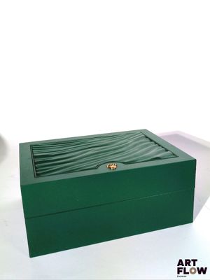 une boîte verte posée sur une table, sur laquelle se trouve une bague en or