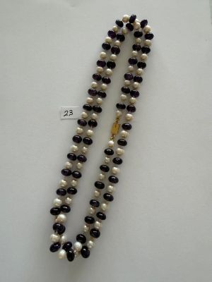 a close up of a necklace with pearls and a gold clasp