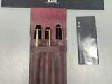 trois stylos dans un étui en cuir posé sur une table