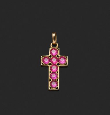 un pendentif en forme de croix en or orné de pierres roses sur fond noir