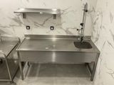 a stainless steel sink in the corner of a bathroom