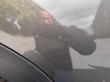 a man taking a picture of himself in the reflection of a car window