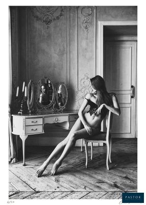 black and white photograph of a woman sitting in a chair in front of a mirror