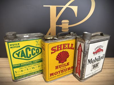 three vintage shell oil cans are lined up on a table