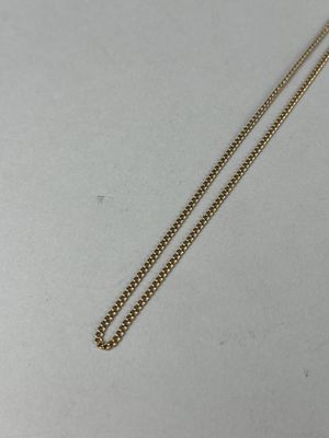 a gold necklace with a chain attached to it on a white surface
