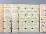quatre livres ornés de motifs décoratifs sont alignés les uns à côté des autres