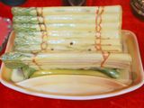 a plate of asparagus wrapped in plastic wrap on a red table cloth