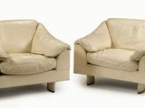 une paire de fauteuils en cuir crème, avec accoudoirs et pieds, sur fond blanc