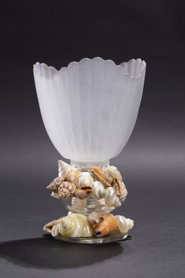 un vase en verre orné de coquillages, posé sur une table