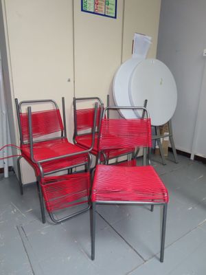 quatre chaises rouges placées dans une pièce, à côté d'un réfrigérateur