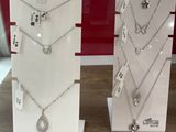 two display stands with necklaces and earrings on them in a store