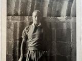 an old black and white photo of a man leaning against a wall