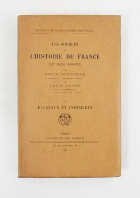 un vieux livre posé sur une table à côté d'un mur blanc
