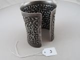 a silver bracelet that is on a table with a price tag
