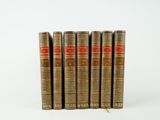 six vieux livres sont alignés sur une surface blanche