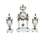une horloge blanche et dorée et deux vases posés sur une table blanche