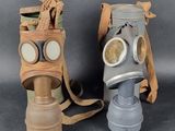 pair of gas masks with goggles on each of them on a gray background