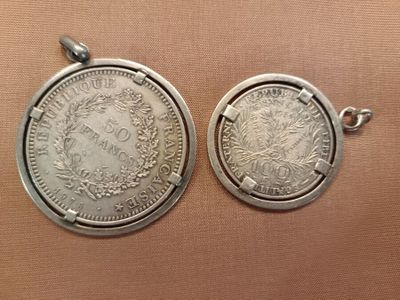 two silver coin pendants, one with a crown and the other with a wreath