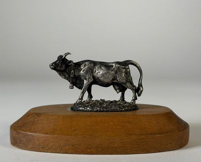 statue d'un taureau posée sur un socle en bois, sur fond blanc