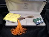 une valise ouverte ornée d'un pompon jaune et d'un bloc-notes