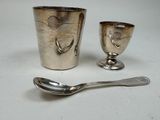 une tasse et une cuillère en argent posées l'une à côté de l'autre sur une table