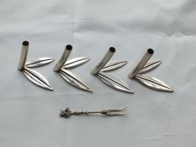 four silver metal spikes and a screw on a white sheet