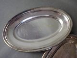 two silver plates sitting on a table next to each other