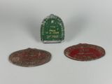 two small metal badges with a red and green design on them