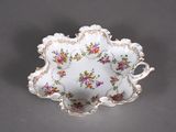 a small white bowl with flowers on it on a table